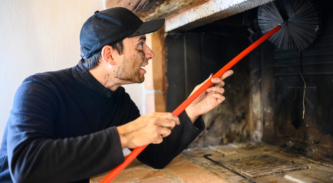 Chimney sweep in action, sweeping a chimney from the fireplace