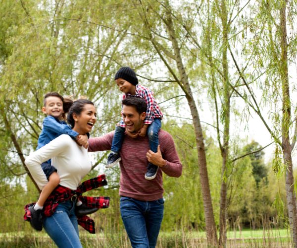 family of four with mum and day carrying the children and having fun