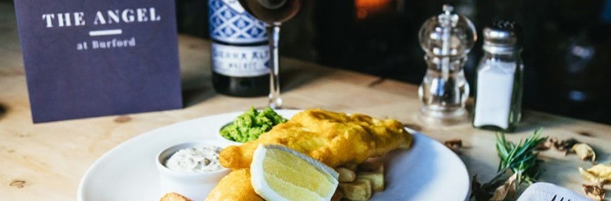 Food on the table with a glass of wine at The Angel dog friendly pub in Burford