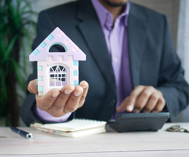 Holiday letting agent holding model home and with calculator