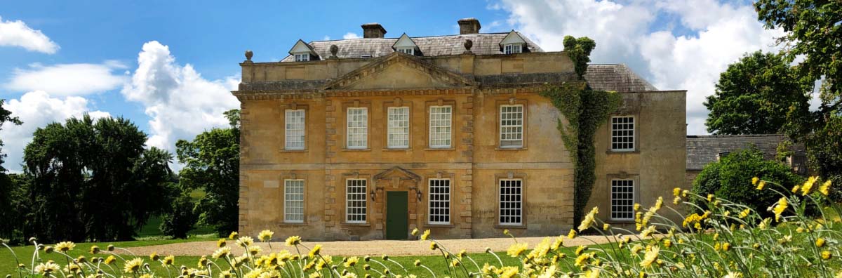 Stunning frontage and lawn of Broadwell Manor with green grass and daffodils